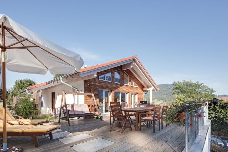 Die Terrasse des Bungalows aus Holz auf Hanggrundstück mit ausgebautem Keller mit viel Glas