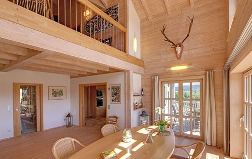 Der Essbereich samt Galerie des Holzhauses im Landhausstil mit Holzfassade und mehrere Balkonen, drei Giebeln und vielen Fenstern