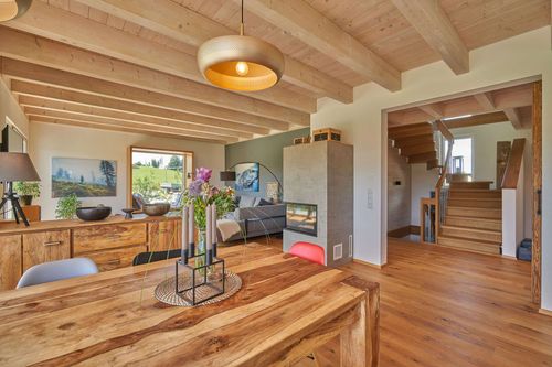 Der Wohn- und Essbereich des modernen Holzhauses im Landhausstil mit durchgängiger Lärchenholzfassade und Holz-Alu-Fenstern