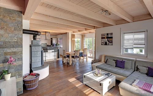 Der Wohn- und Essbereich des Holzhauses im Landhausstil mit gemischter Fassade aus mineralischem Putz und Holz