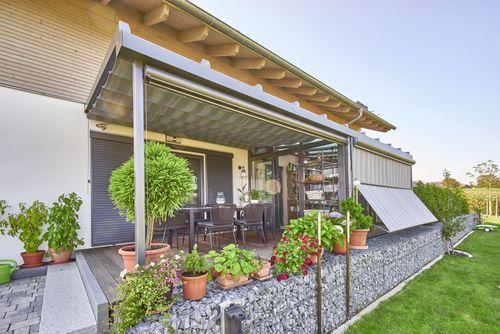 Die überdachte Terrasse samt Wintergarten des modernen Holzhauses mit Mischfassade aus Holz und Putz und komfortabler Ausstattung